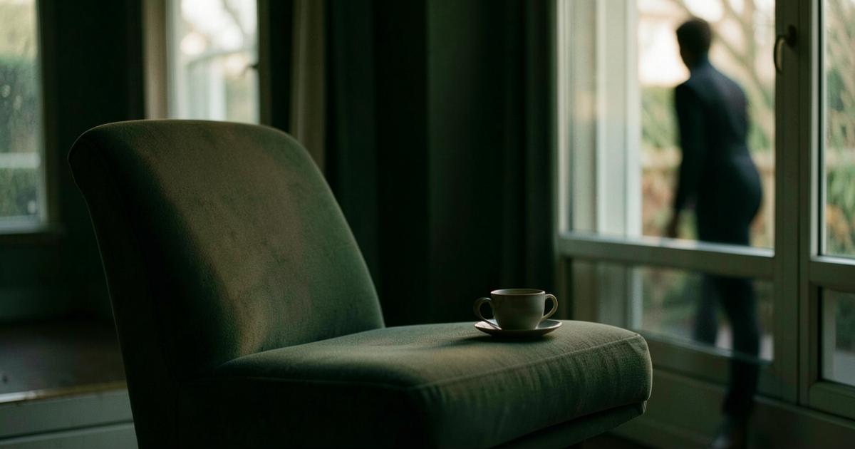 Fauteuil vide près d'une fenêtre avec une tasse abandonnée, une silhouette floue s'éloignant dehors